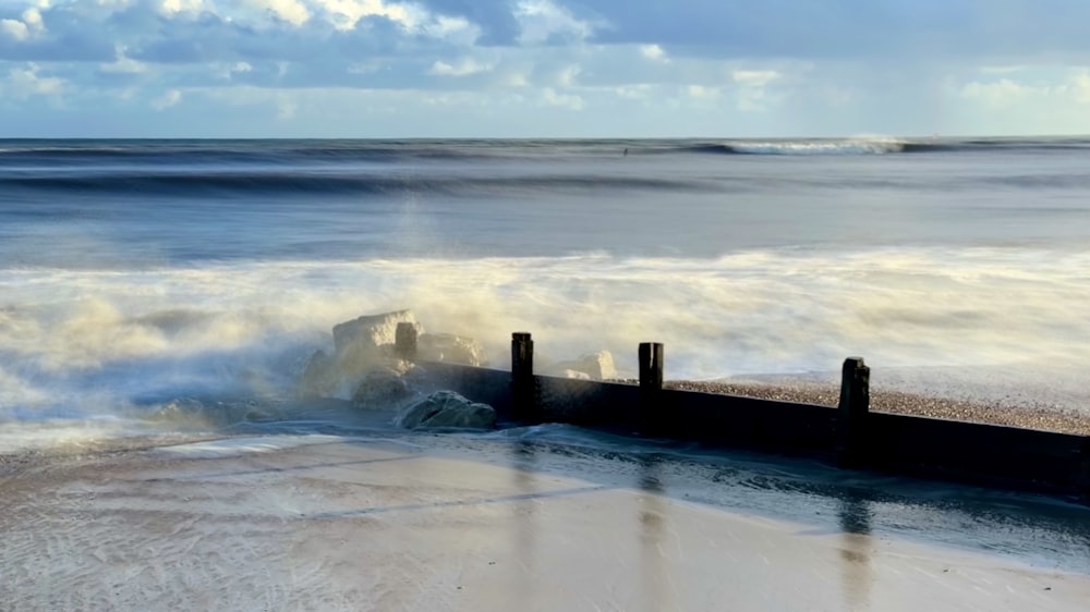 waves crashing onto a pier on a beach
