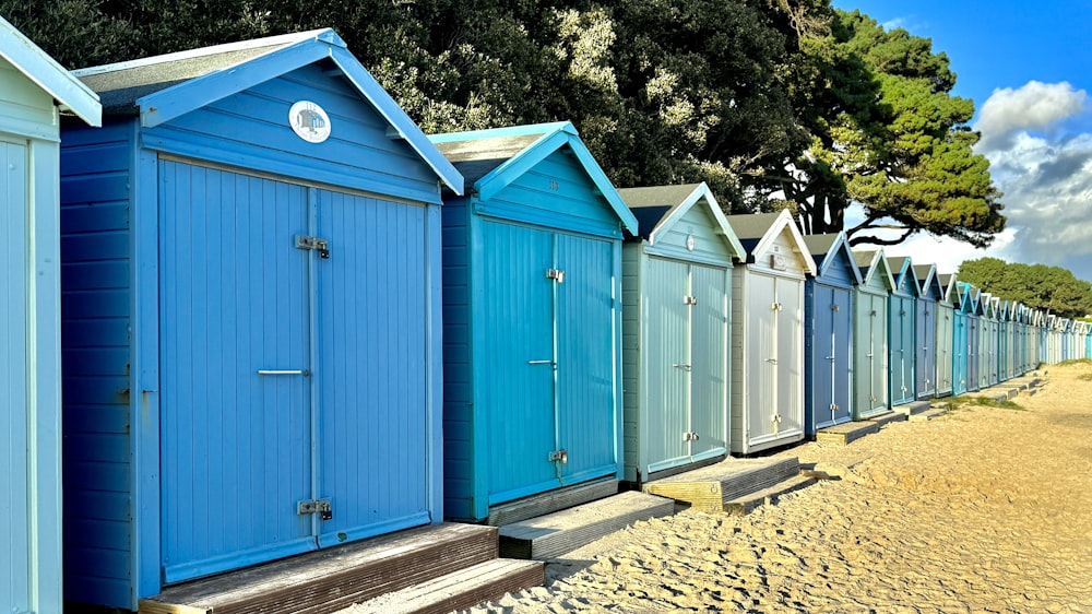 uma fileira de cabanas de praia sentados em cima de uma praia de areia