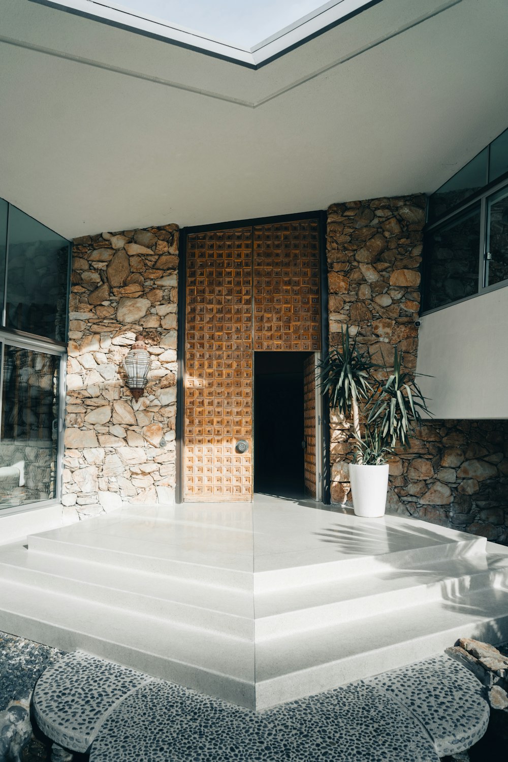 a house with a stone wall and a potted plant