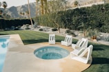 a swimming pool with lawn chairs and a hot tub
