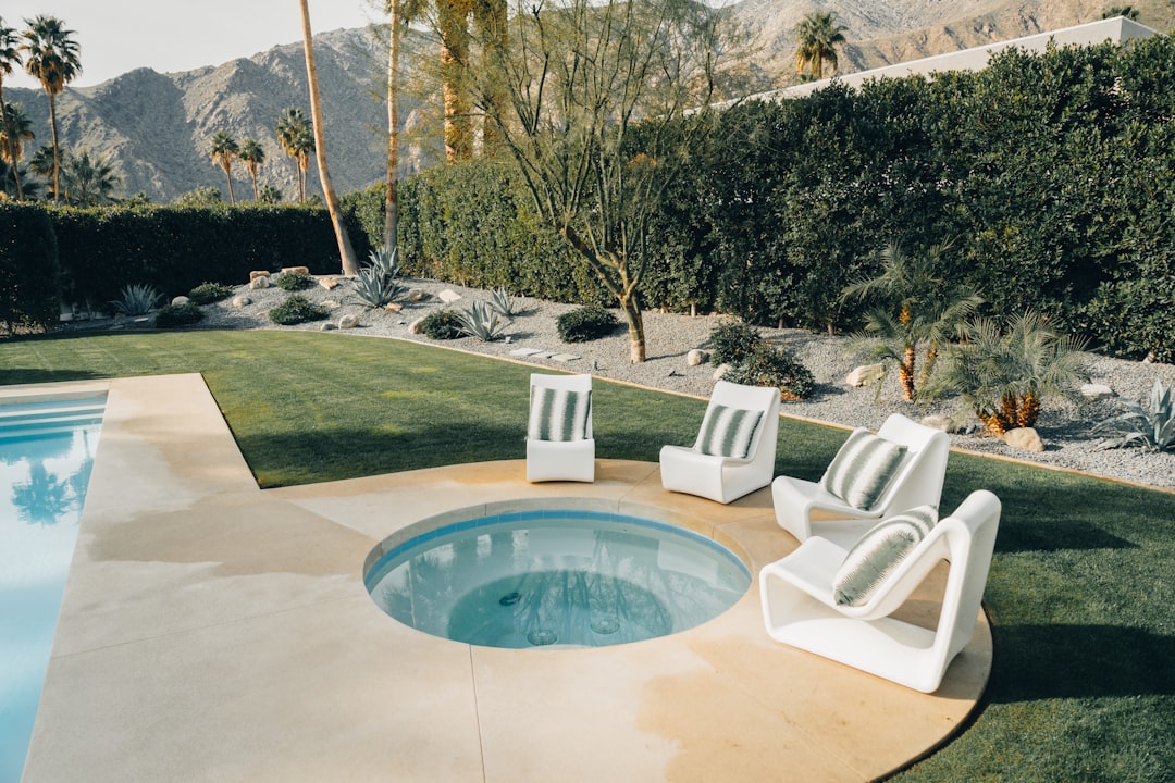 a swimming pool with lawn chairs and a hot tub,