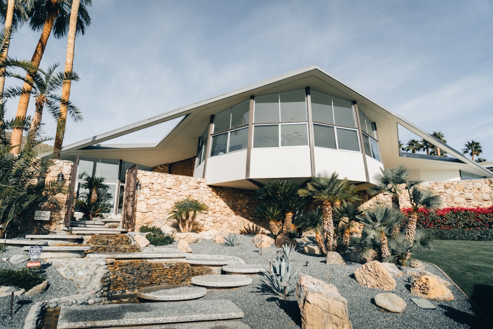 a modern house with palm trees and landscaping