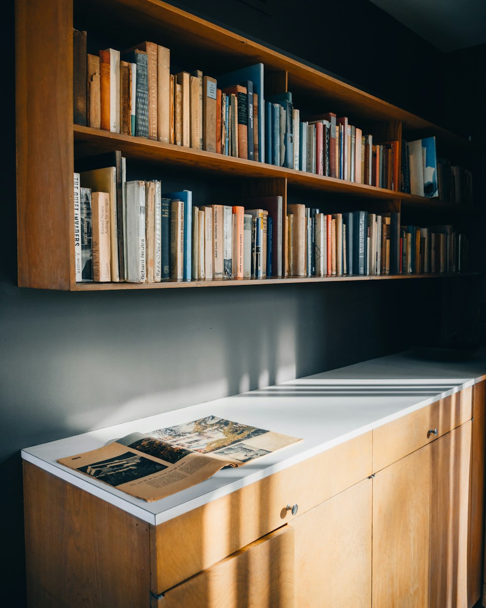a bookshelf filled with lots of books next to a white counter