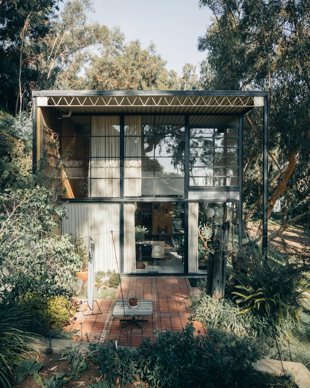 a small house with a lot of plants and trees around it