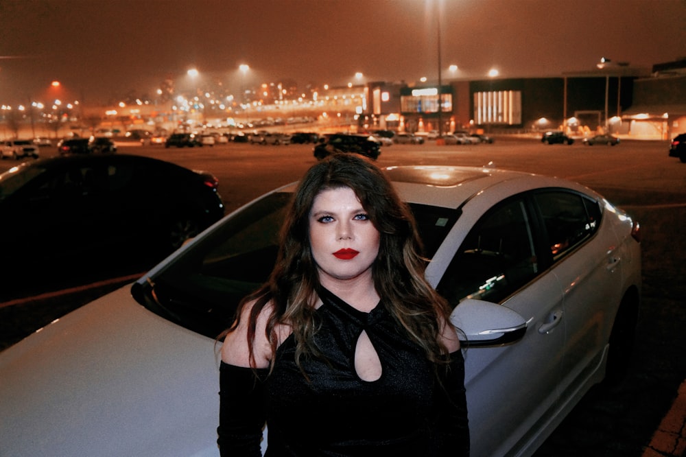 a woman standing next to a car in a parking lot
