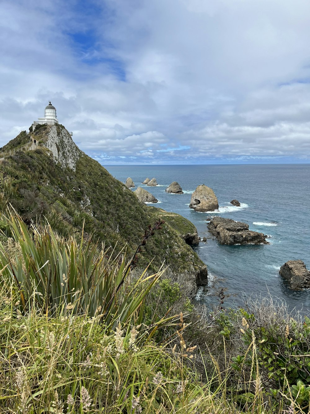 a view of the ocean with a lighthouse on top of a hill