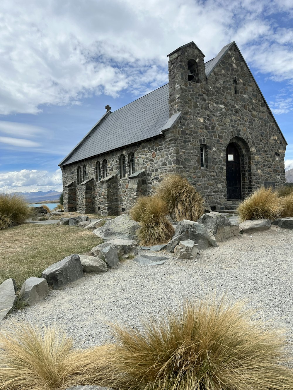 a stone church surrounded by grass and rocks