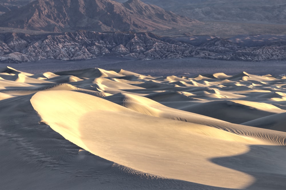 sand dunes in the desert with mountains in the background