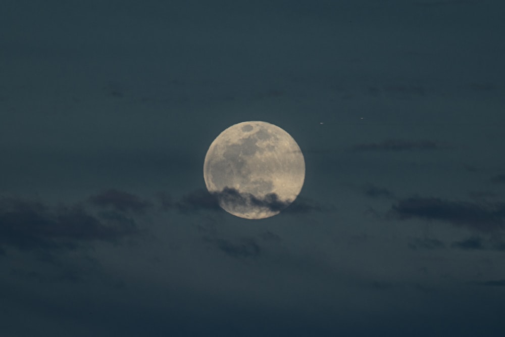 a full moon is seen through the clouds