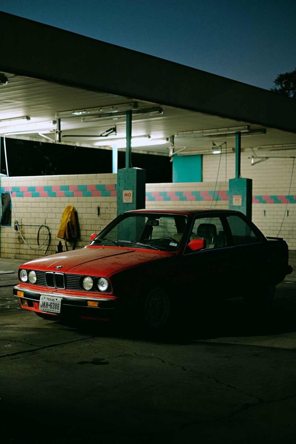 a red car parked in front of a gas station