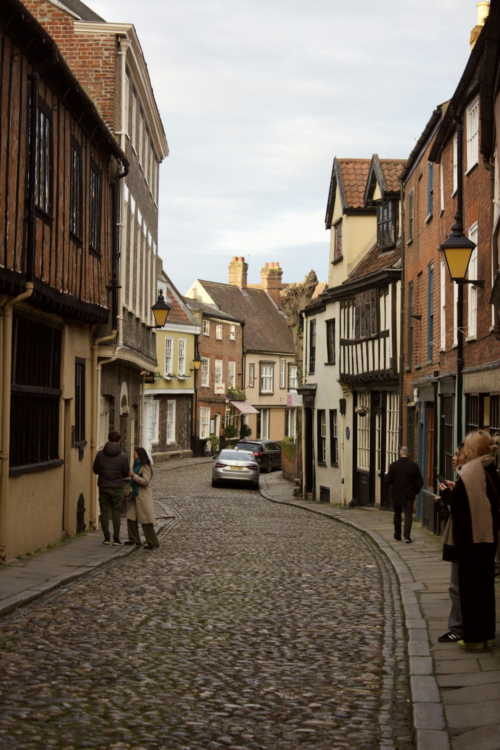 a cobblestone street with a car parked on the side