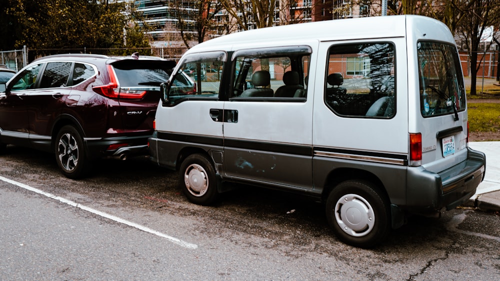 a white van parked next to a red car on the side of the road