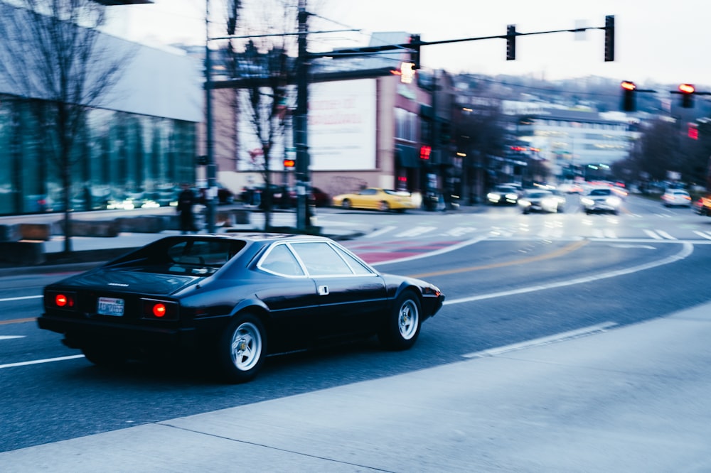 a black car driving down a street next to a traffic light