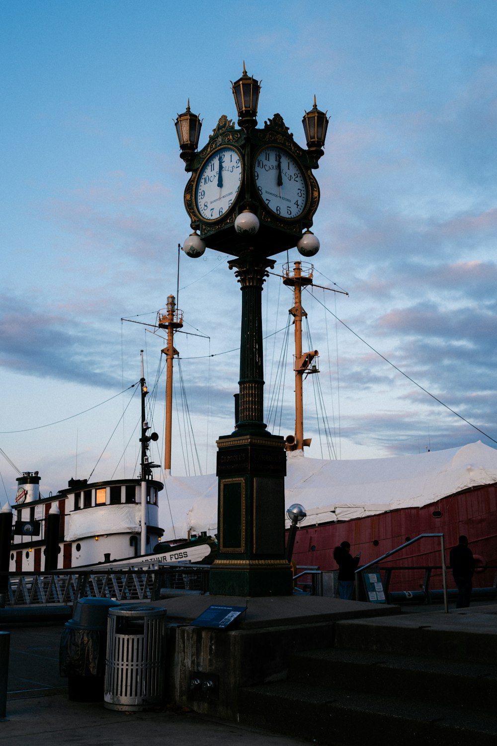 a clock on a post in front of a boat