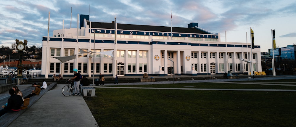 a large white building with people sitting on the side of it