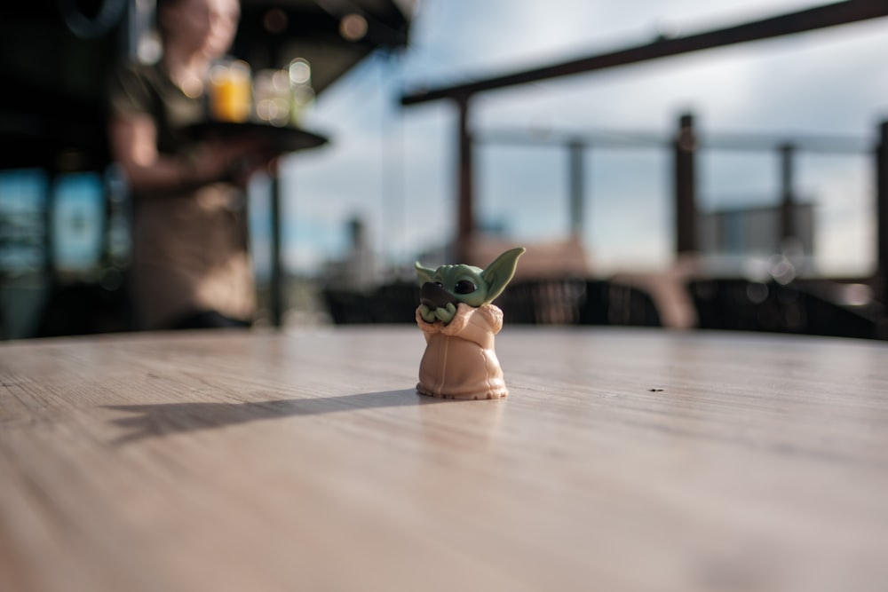 a baby yoda toy sitting on top of a wooden table