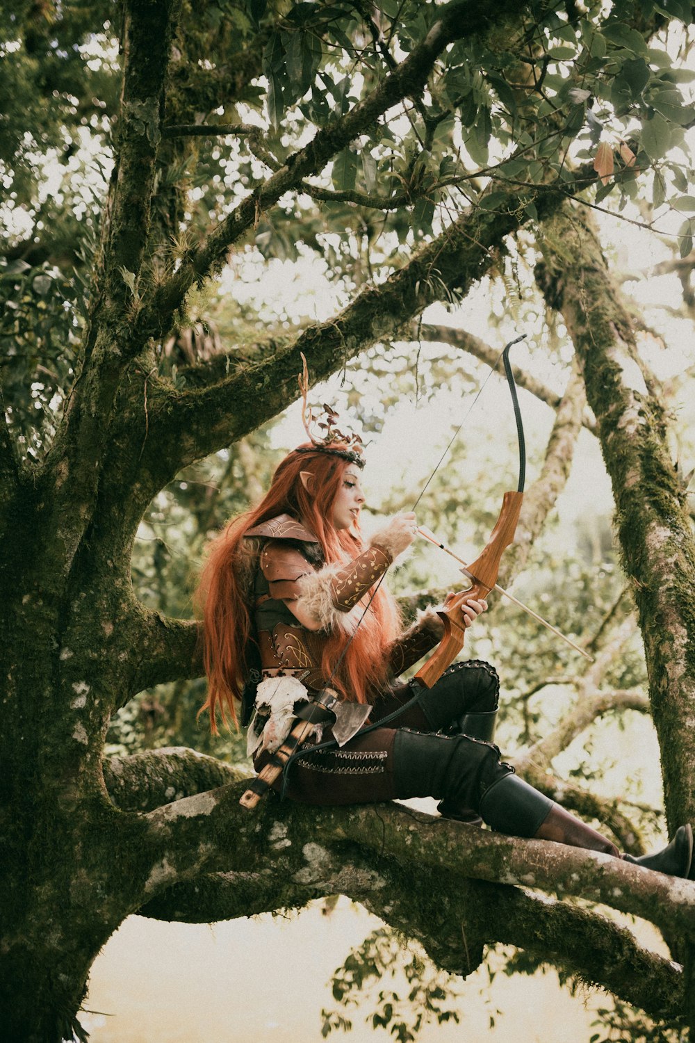 a woman with red hair sitting on a tree branch