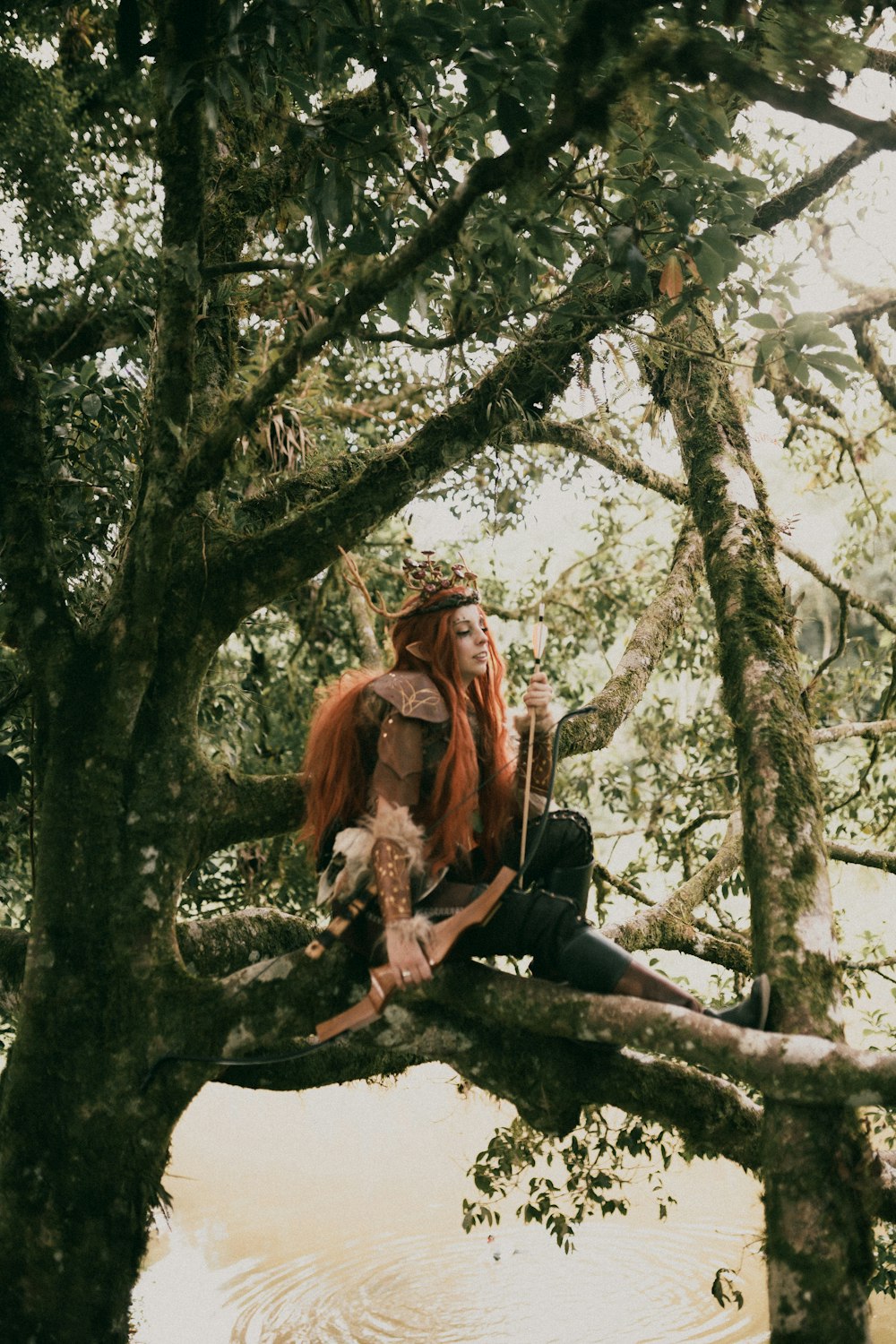 a woman with red hair sitting on a tree branch