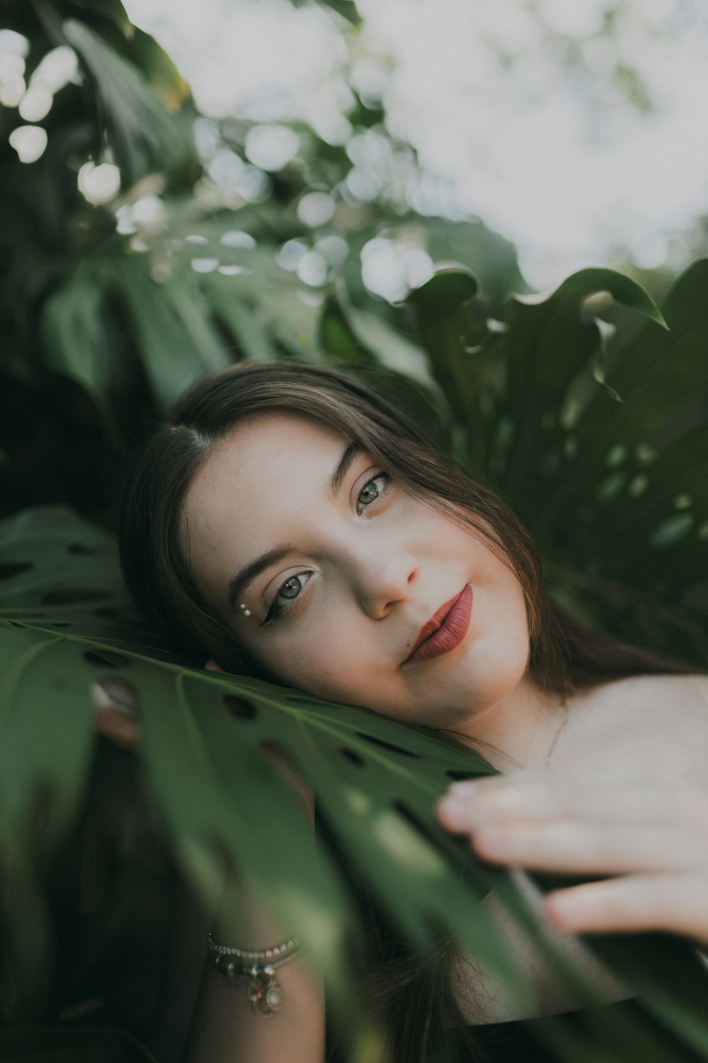 a woman is posing for a picture in a leafy area