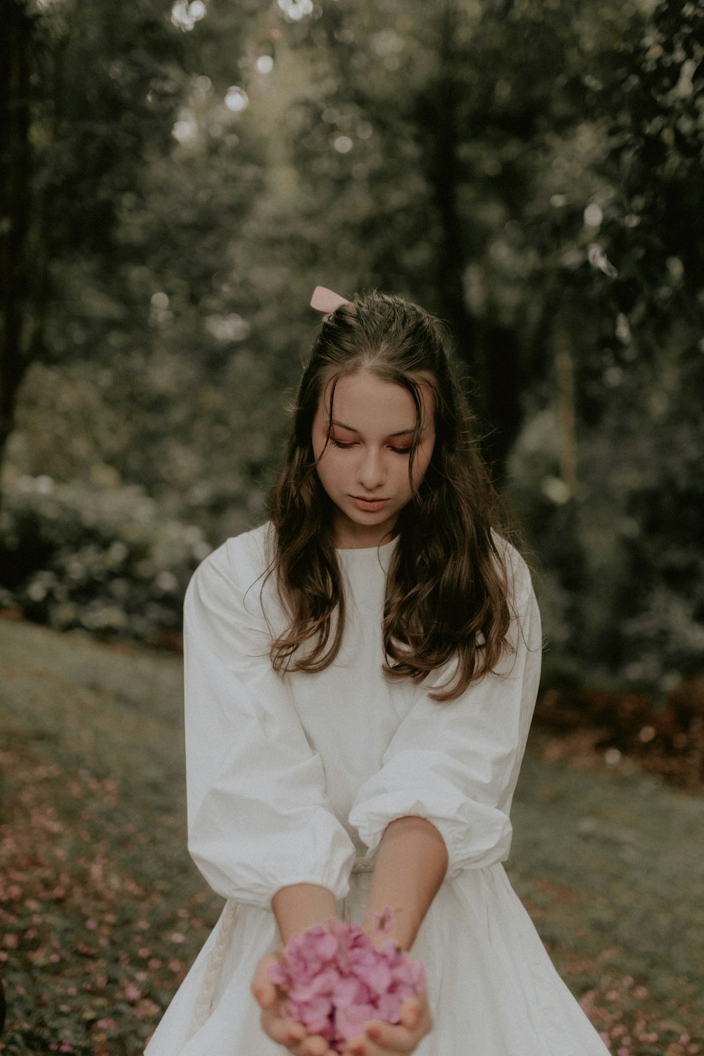 a girl in a white dress holding a pink flower