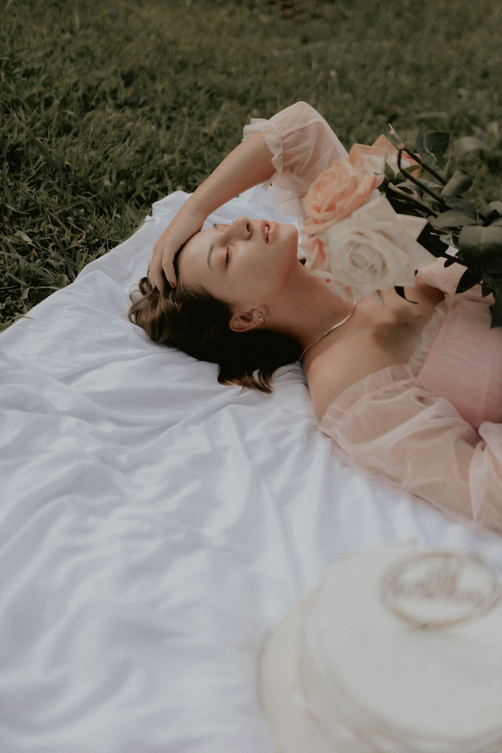 a woman laying on a blanket with a bouquet of flowers