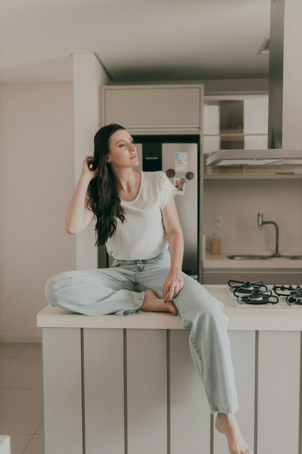 a woman sitting on a counter in a kitchen