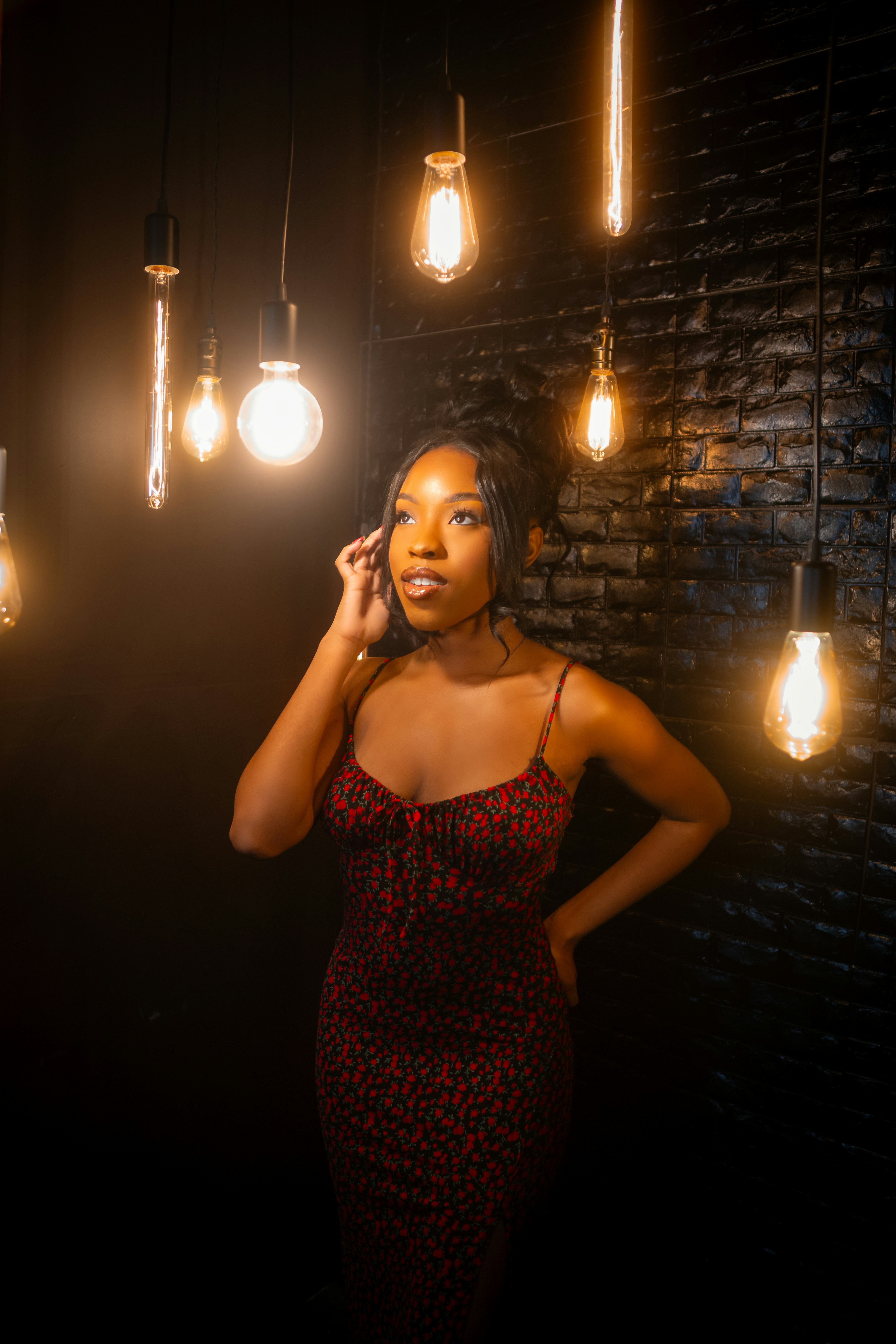 a woman standing in front of a brick wall talking on a cell phone