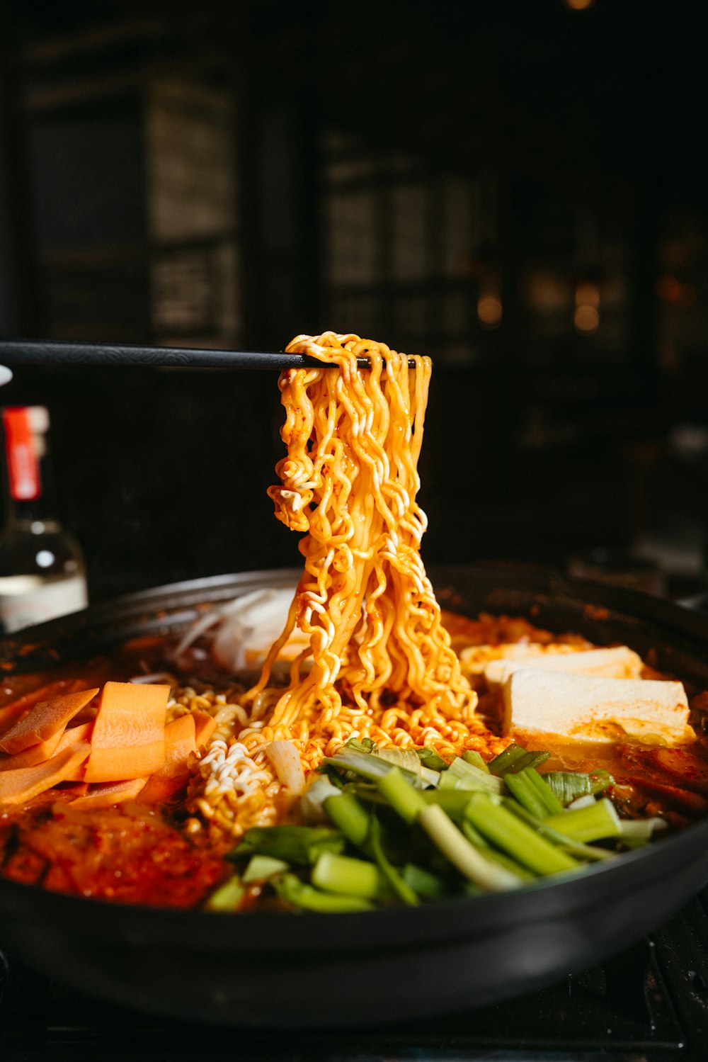 a bowl of ramen being lifted with chopsticks