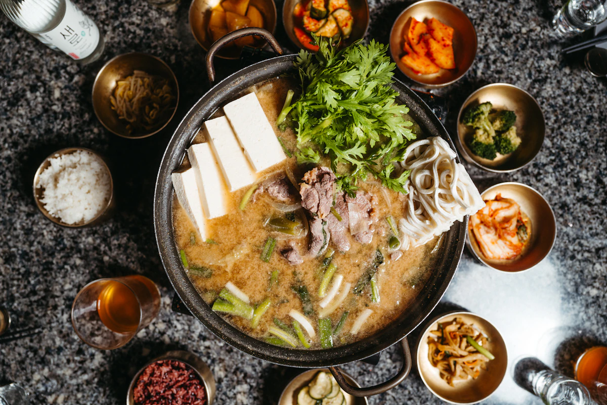 Bát súp xương bò trắng đục ăn kèm đũa trên bàn gỗ
