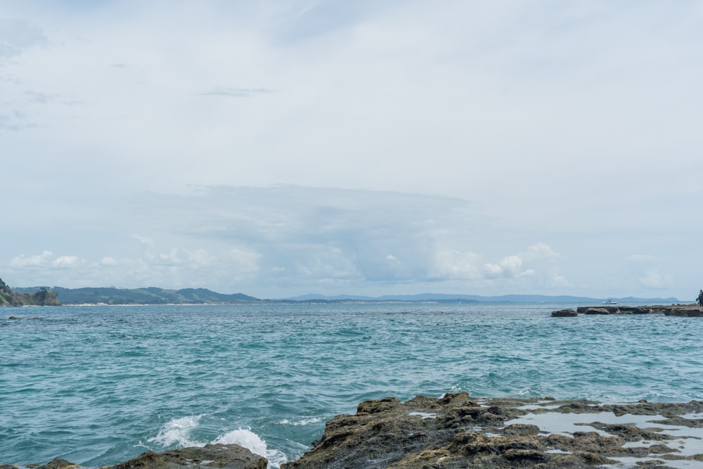 a large body of water sitting next to a rocky shore