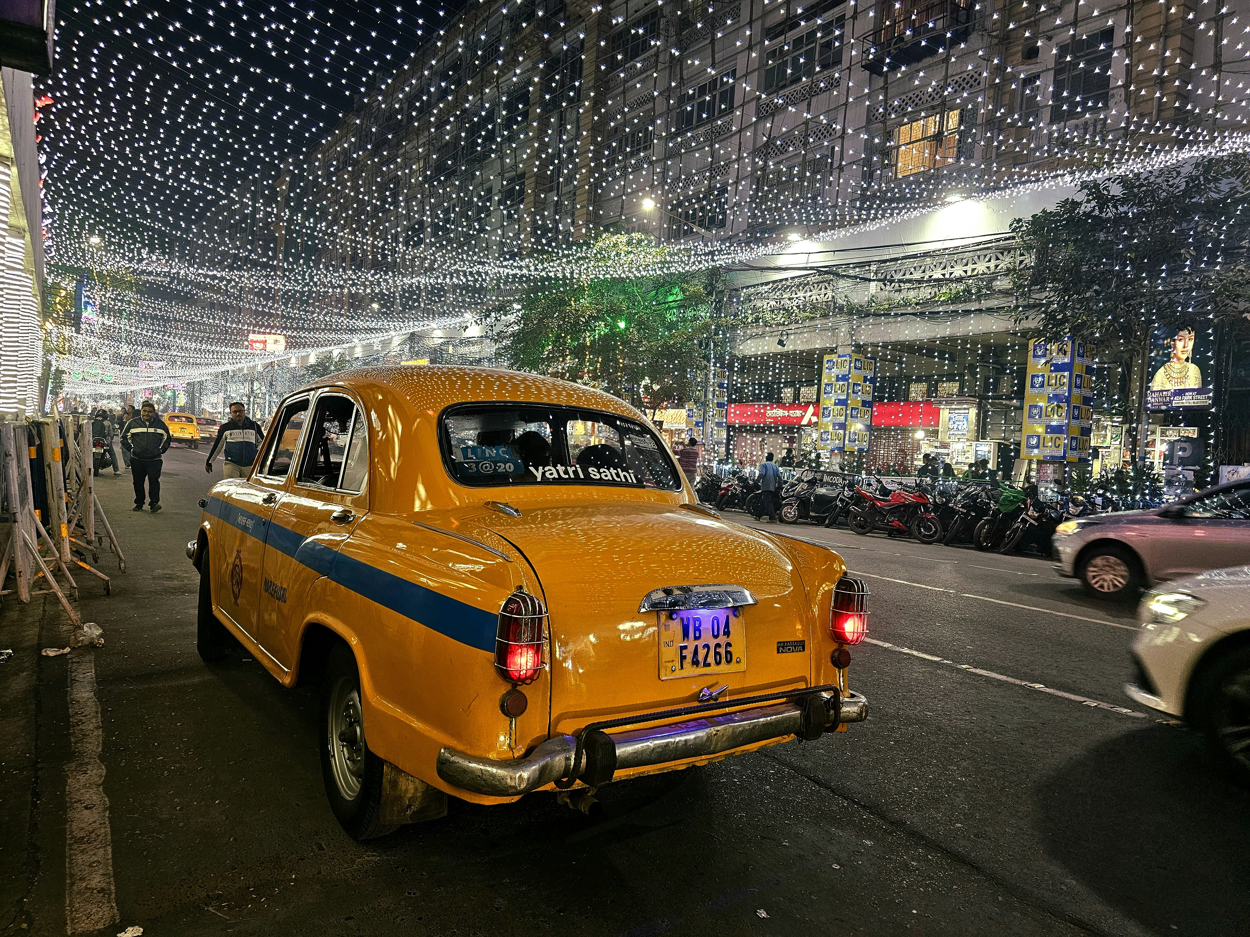 a yellow taxi cab driving down a street next to parked cars