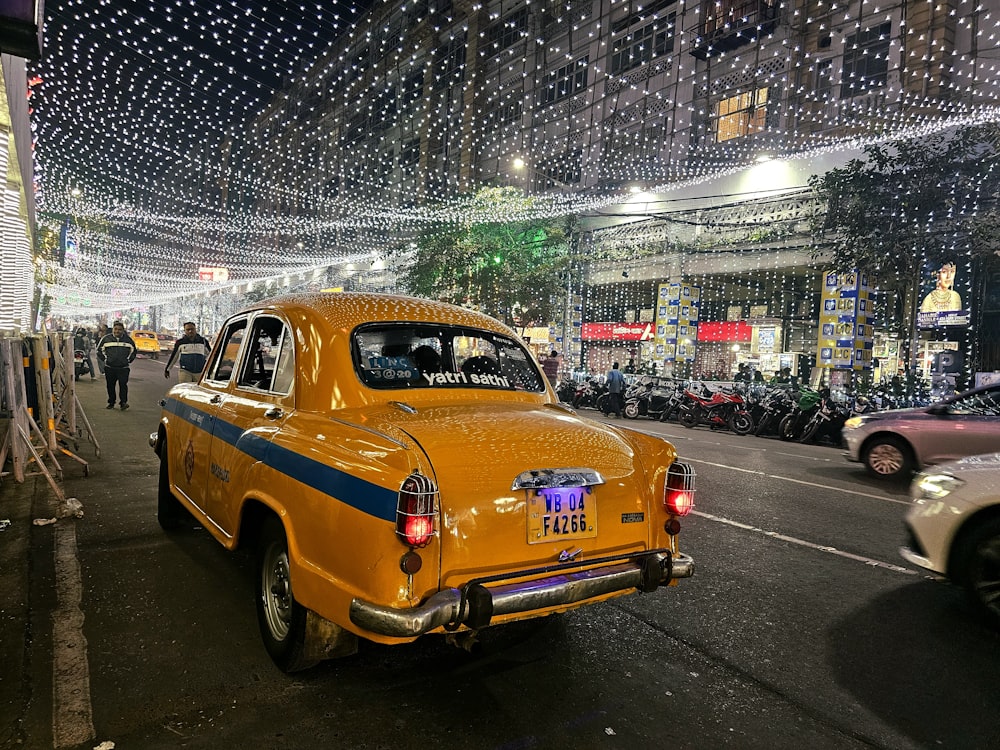 a yellow taxi cab driving down a street next to parked cars