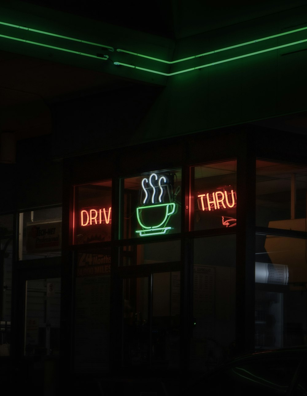 a neon sign that says drive thru and a cup of coffee