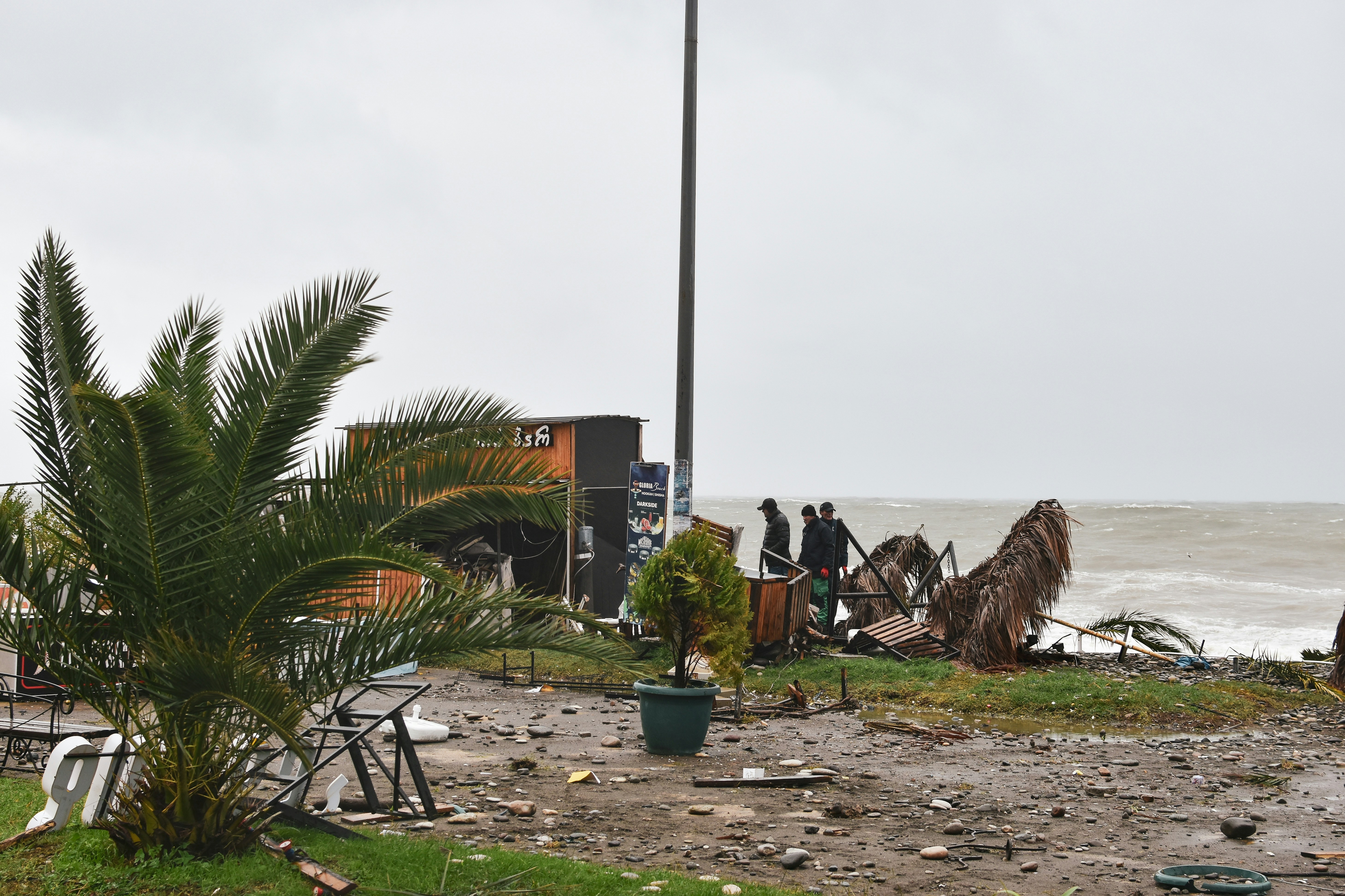 a group of people standing on top of a beach next to the ocean, 
