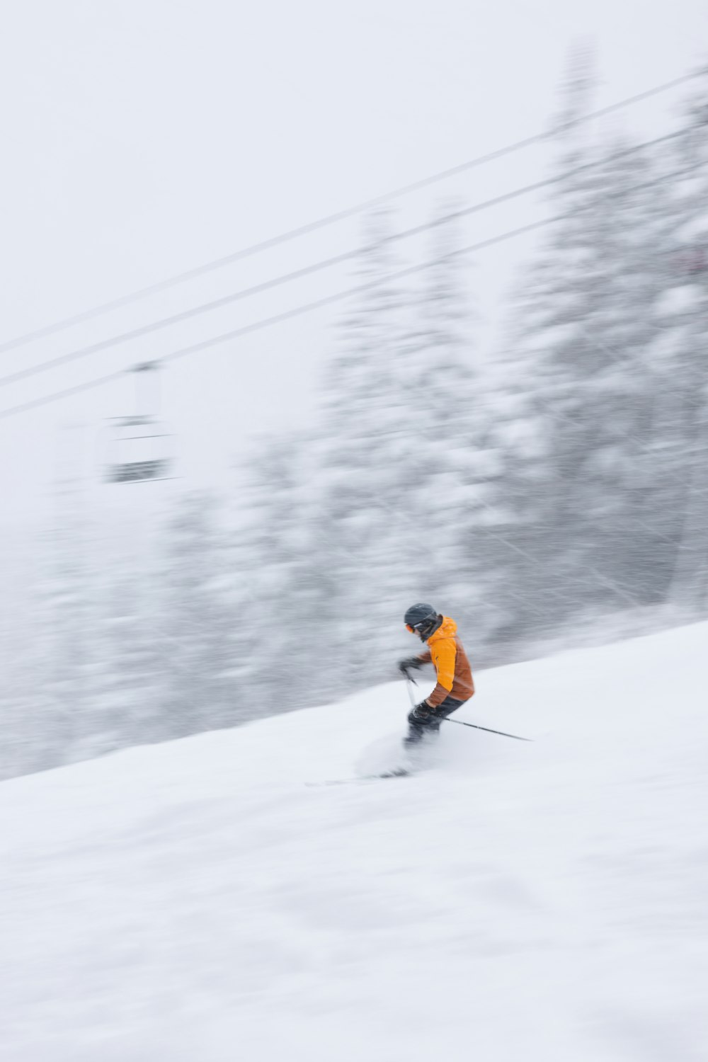 雪に覆われた斜面をスキーで滑り降りる男性