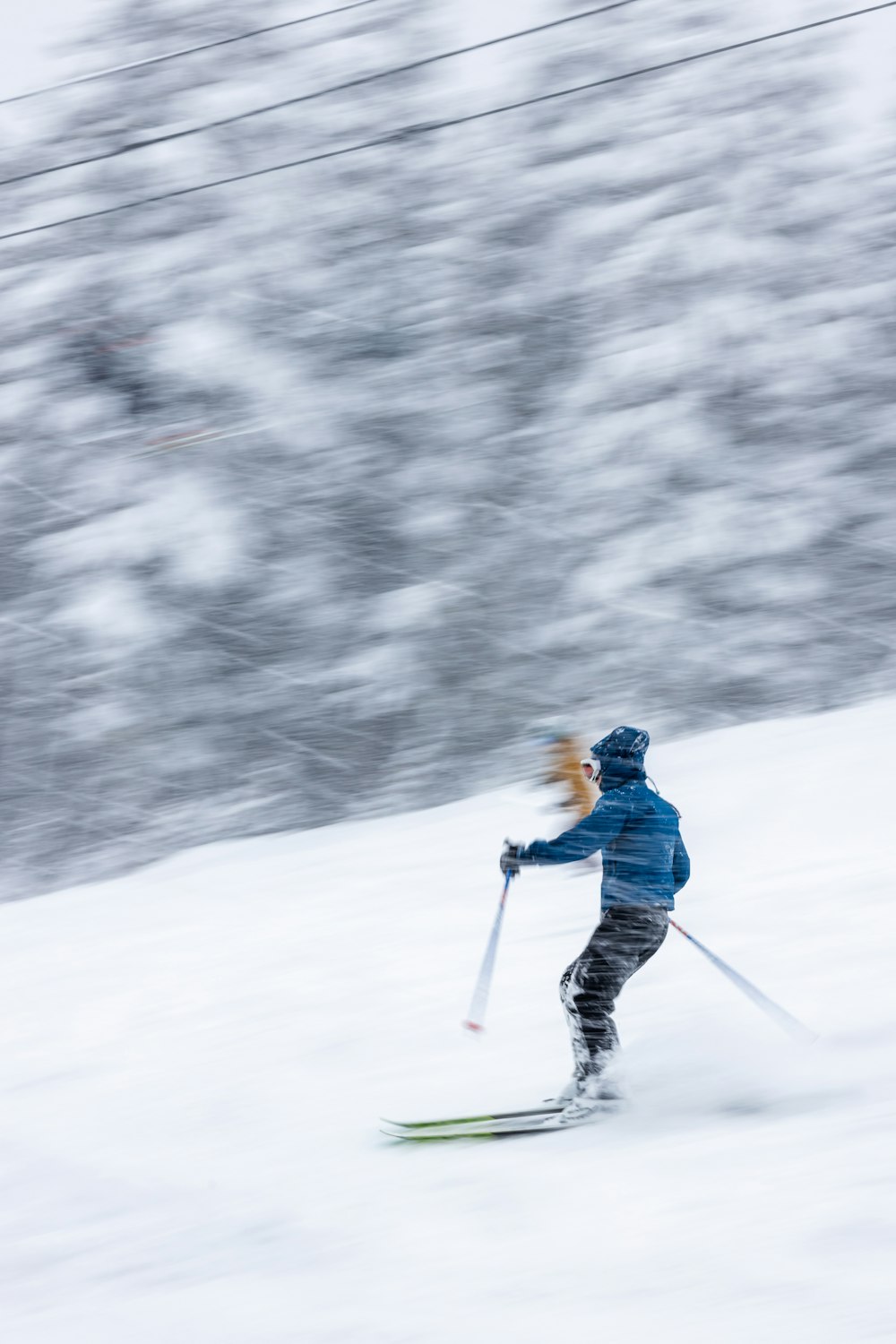 雪に覆われた斜面をスキーで滑り降りる人
