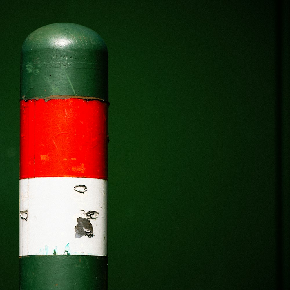 a red, white and green fire hydrant with birds on it