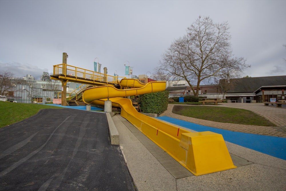 a yellow slide in the middle of a park