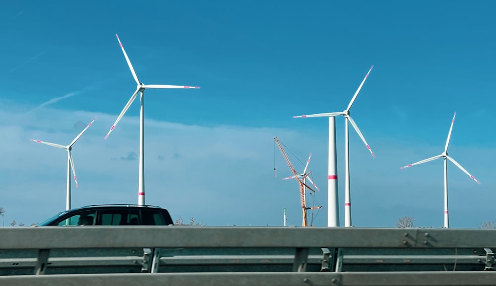 a car driving down a highway next to a bunch of windmills