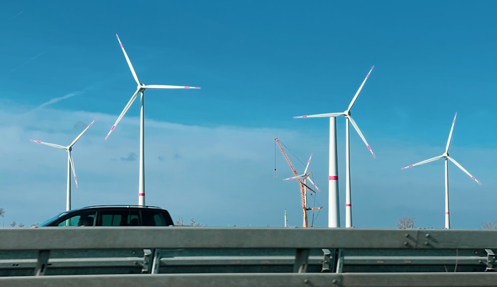 un'auto che percorre un'autostrada accanto a un mucchio di mulini a vento