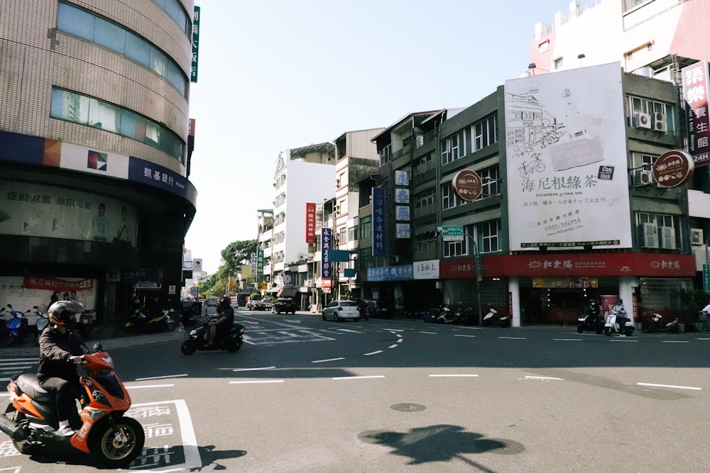 a man riding a motorcycle down a street next to tall buildings