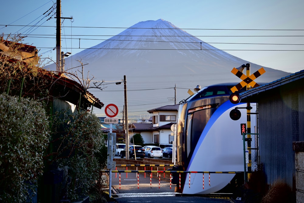 a blue and white train traveling past a tall mountain