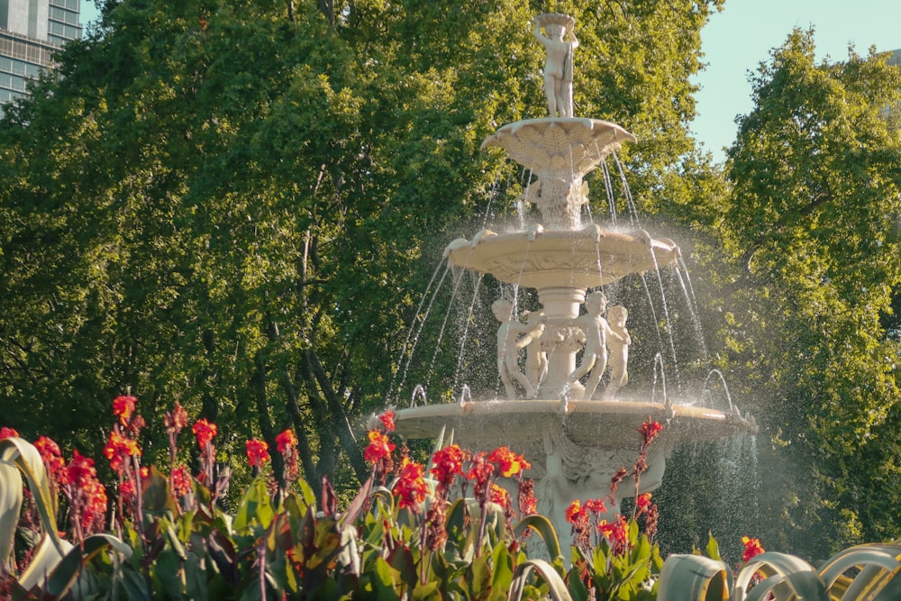a water fountain surrounded by flowers and trees