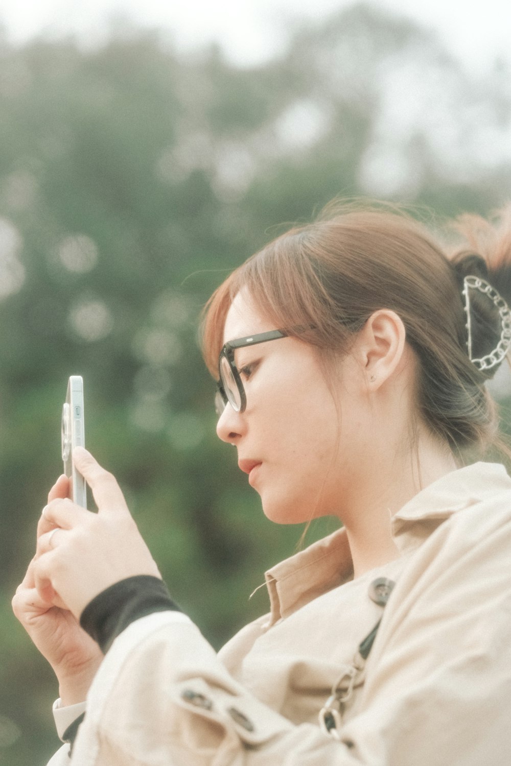 a woman wearing glasses looking at her cell phone