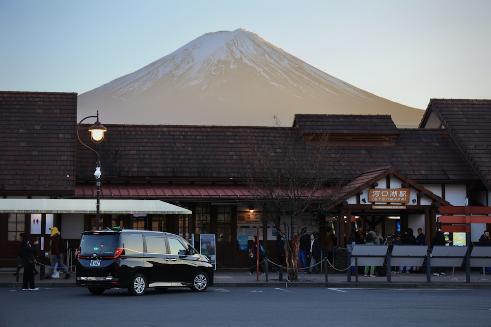a car parked in front of a building with a mountain in the background