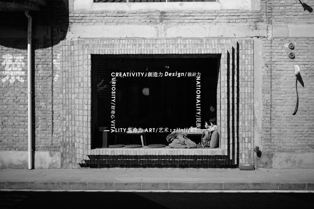 a black and white photo of a man sitting in a window