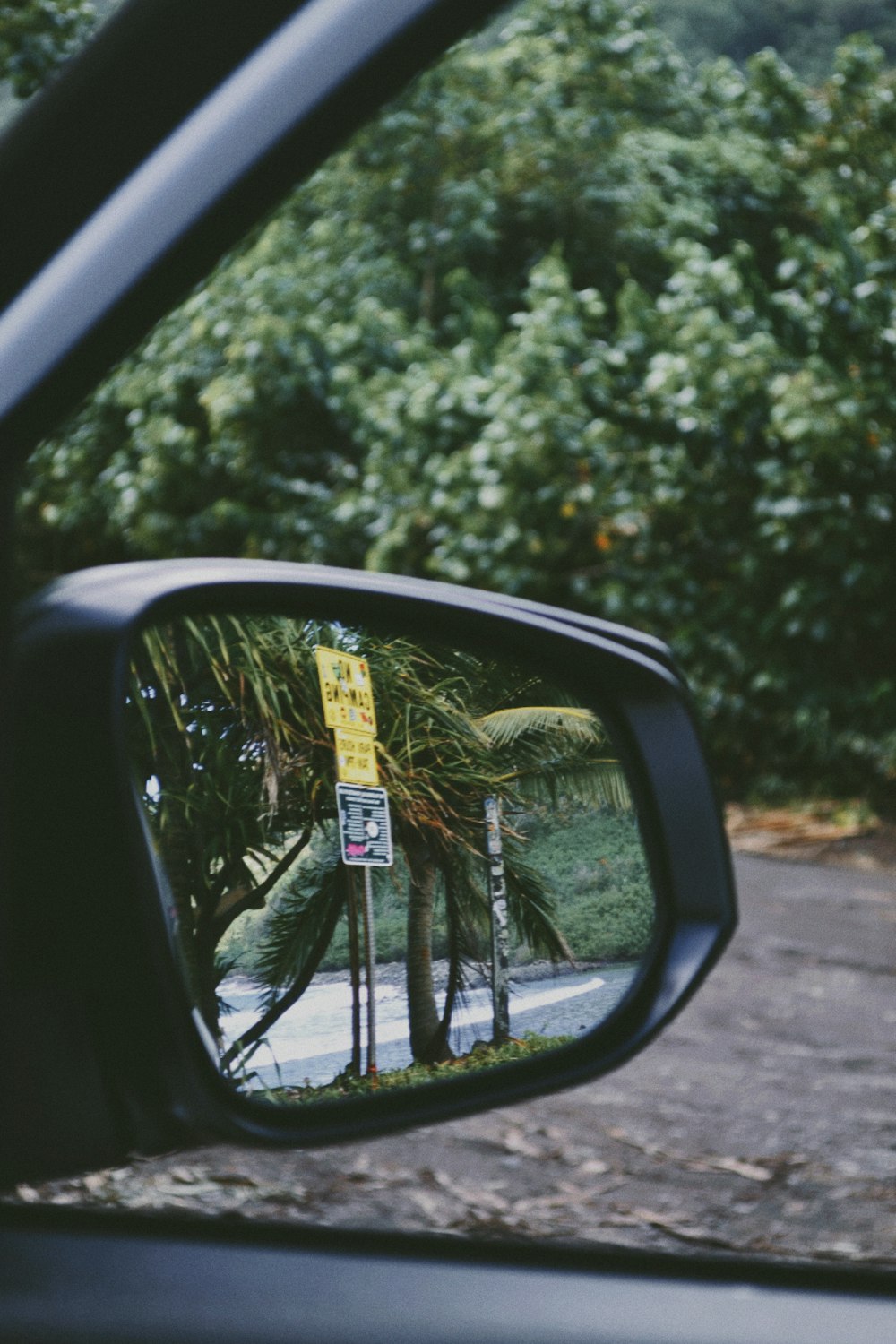 a side view mirror with a street sign in the reflection