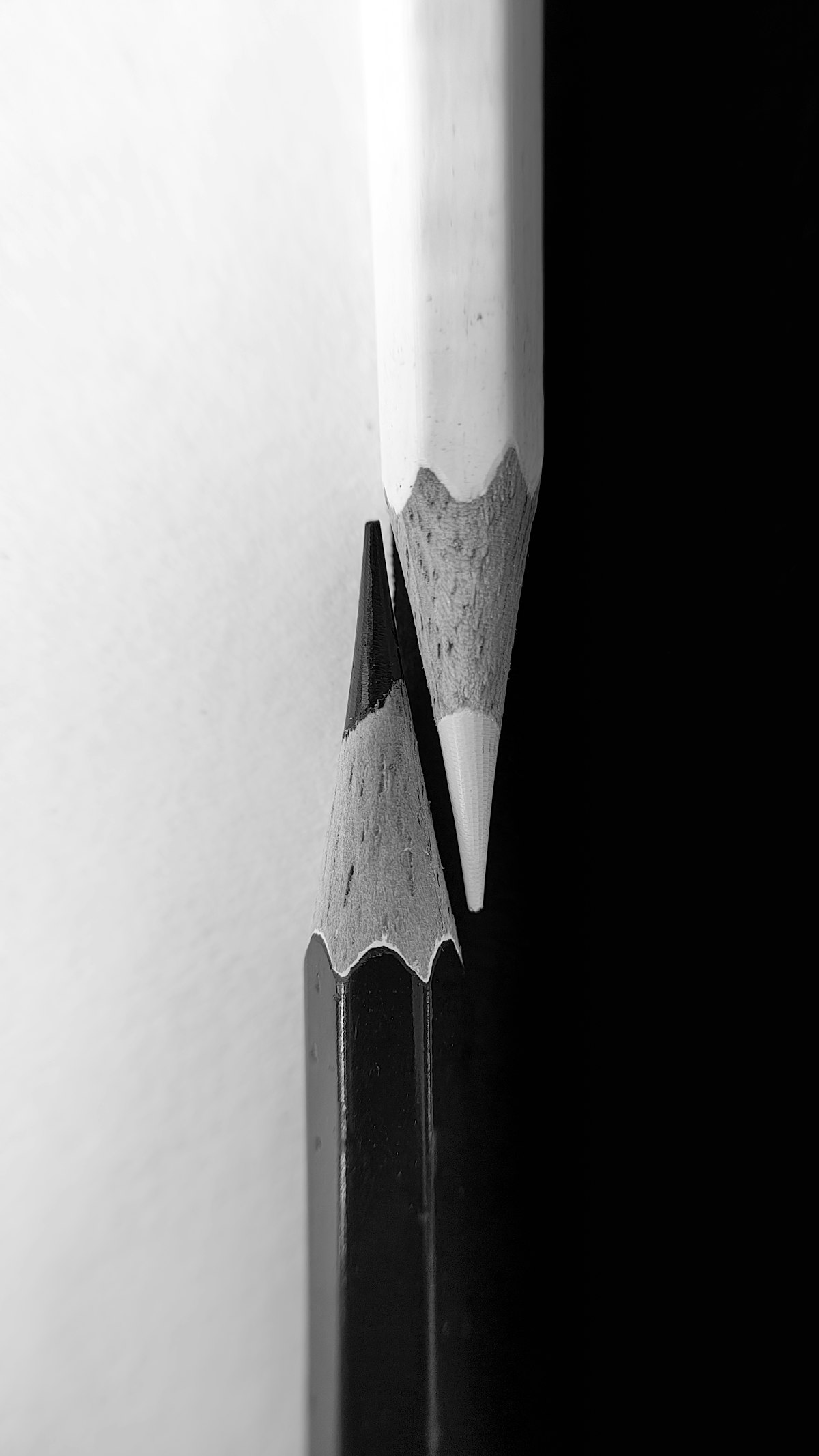 Two sharpened pencil tips, one white and one black, meeting against a split light-and-dark ground, give-every-dollar-a-job register