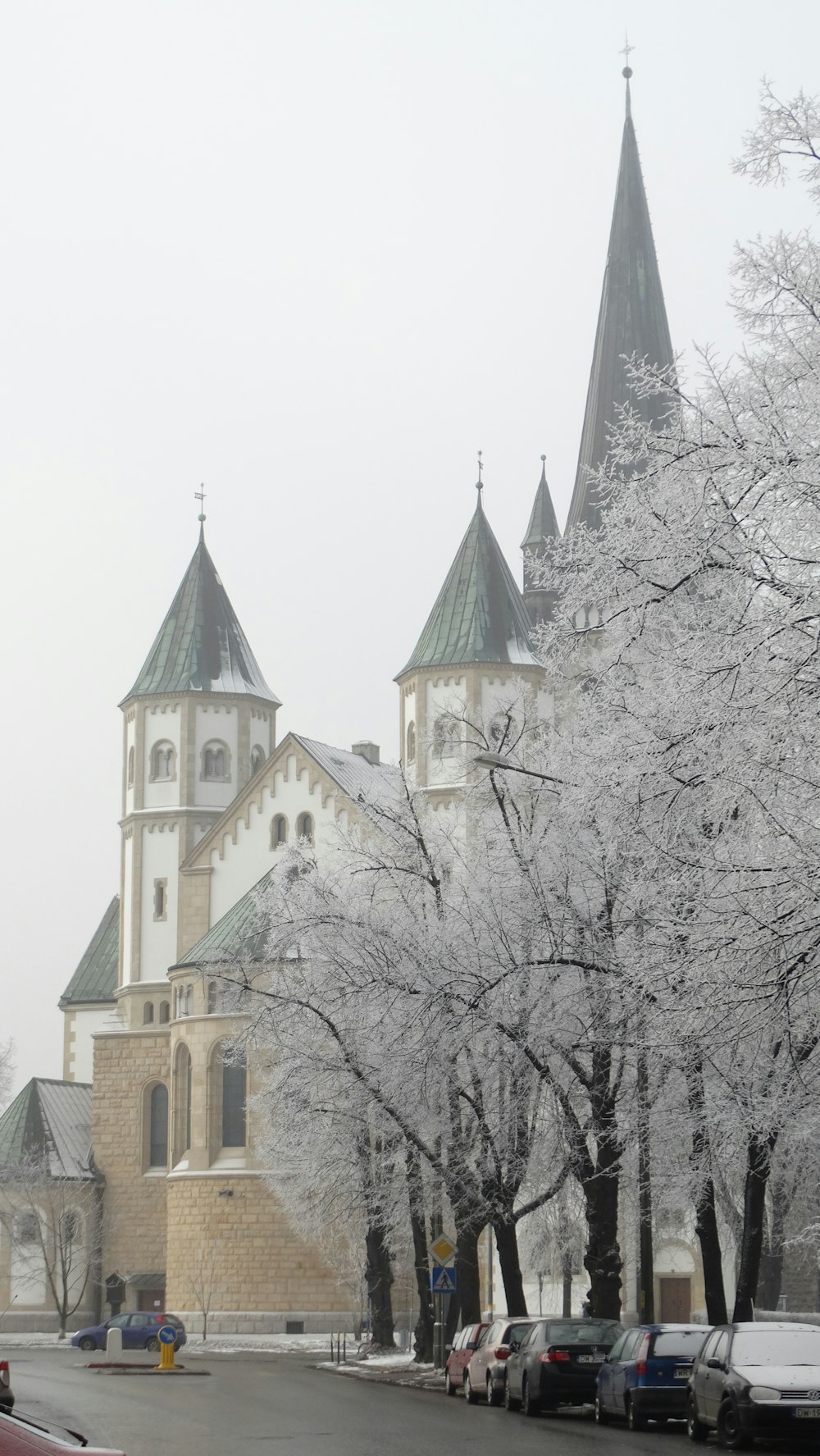 a large church with a steeple surrounded by snow covered trees