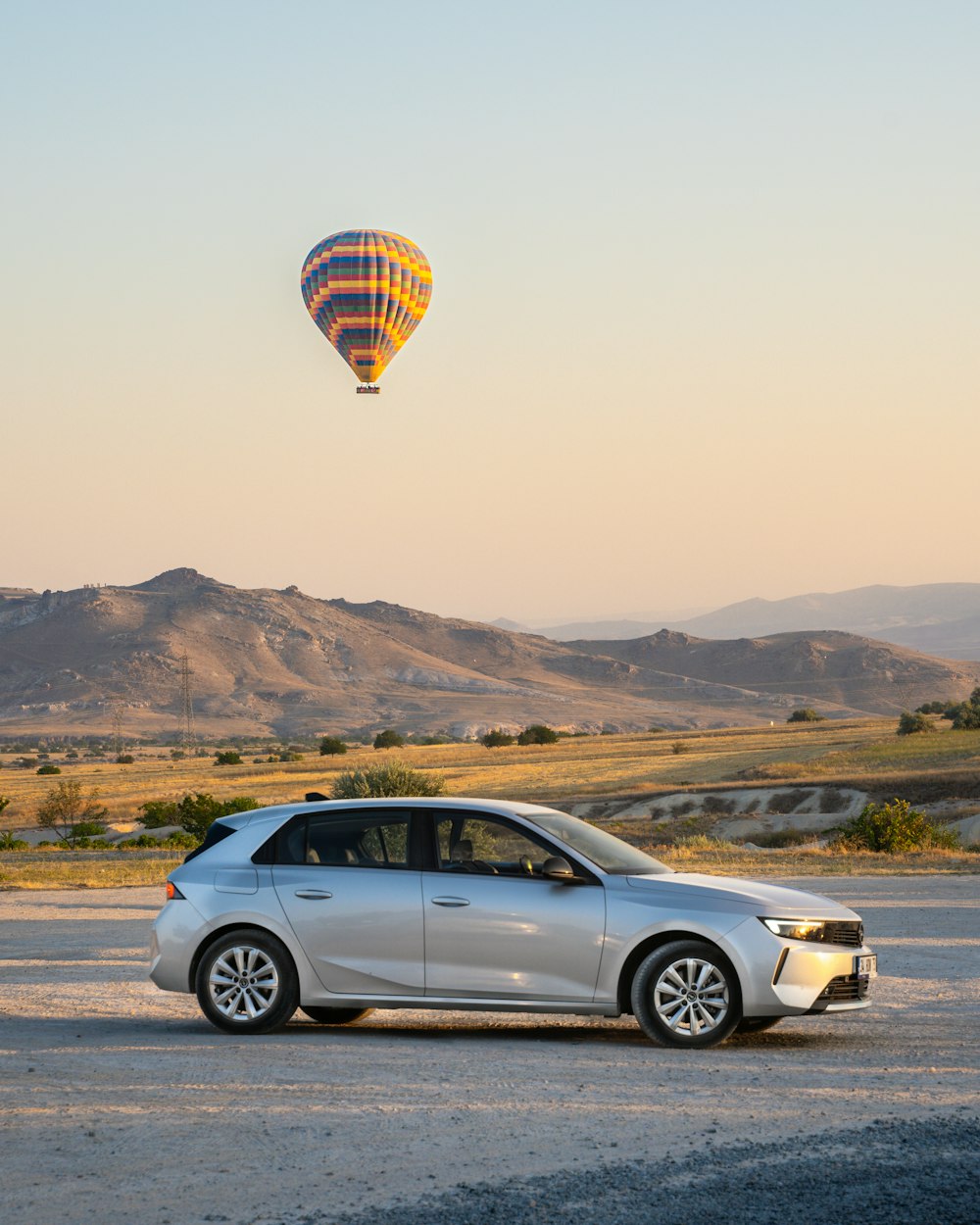 a car parked in a parking lot with a hot air balloon in the sky